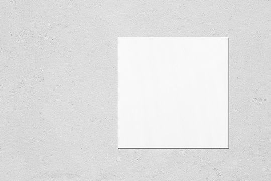 Empty white square flyer or business card mockup with soft shadows on neutral light grey concrete background. Flat lay, top view