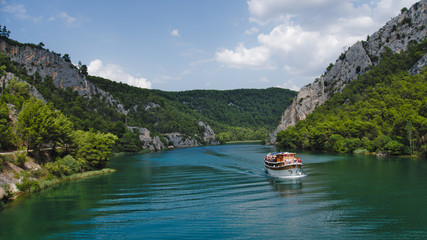 A boat flowing down the river with mountains in the background