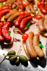 homemade sausages lie on a table decorated with tomatoes, capers and red pepper