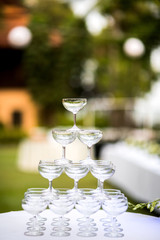 Pyramid of glasses of champagne at outdoor garden in wedding ceremony