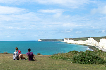 A young couple and child at Birling Gap against the Seven Sisters White Cliffs in East Sussex,...