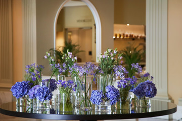 Beautifully arranged purple flowers in flower glass pots on the table. Elegant flowers arrangement.