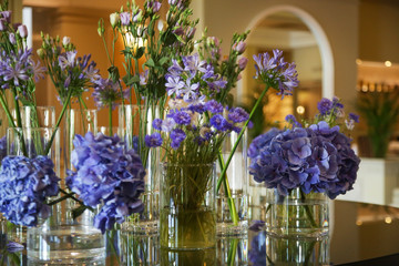 Beautifully arranged purple flowers in flower glass pots on the table. Elegant flowers arrangement.