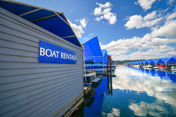 Boats line up in their covered boat slips at a marina next to a boat rental sign in the Pacific Northwest