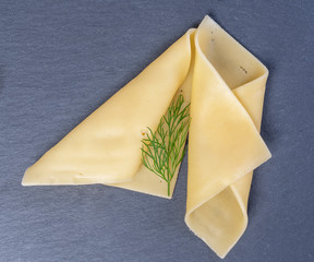  Slices of yellow cheese on a natural background, with vegetables