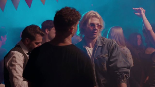 At night young group of friends dancing together enjoying party music having fun celebrating weekend connection cheerful friendship gathering man nightlife entertainment hanging out slow motion