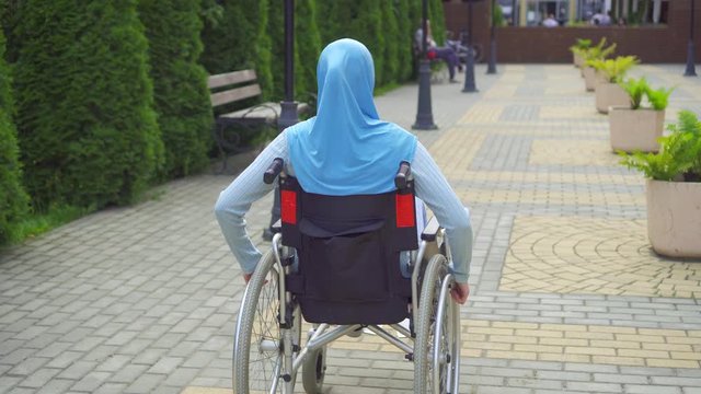 Young arab woman disabled in traditional scarf in a wheelchair
