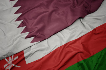 waving colorful flag of oman and national flag of qatar.