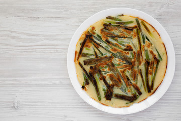 Homemade korean Pajeon scallion pancake on a white plate on a white wooden surface, view from above. Asian food. Flat lay, top view, overhead.