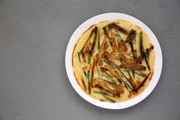 Homemade korean Pajeon scallion pancake on a white plate on a gray surface, top view. Asian food. Copy space.