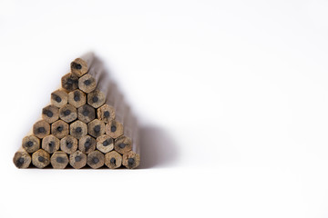 pyramid of wooden unsharpened pencils on a white background