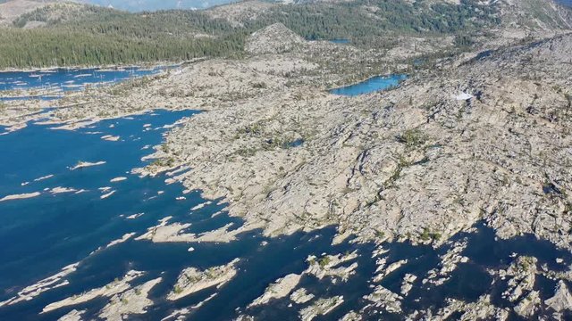 An aerial view shows snow melt surrounding rocky islands in an alpine lake in the Sierra Nevada mountains. These California mountains are made up of 100 million year old granite sculpted by glaciers.