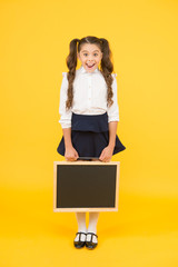 For your information. Happy little kid holding blank blackboard for information on yellow background. Small child smiling with tidy chalkboard for school information. Information board, copy space