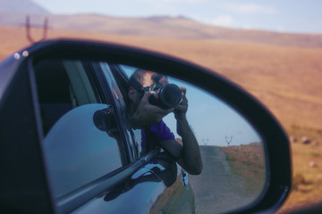 young photographer takes pictures from a car