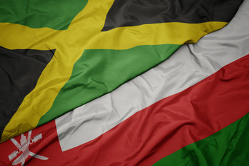 waving colorful flag of oman and national flag of jamaica.