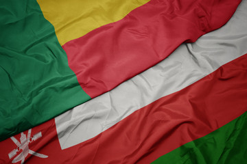 waving colorful flag of oman and national flag of benin.