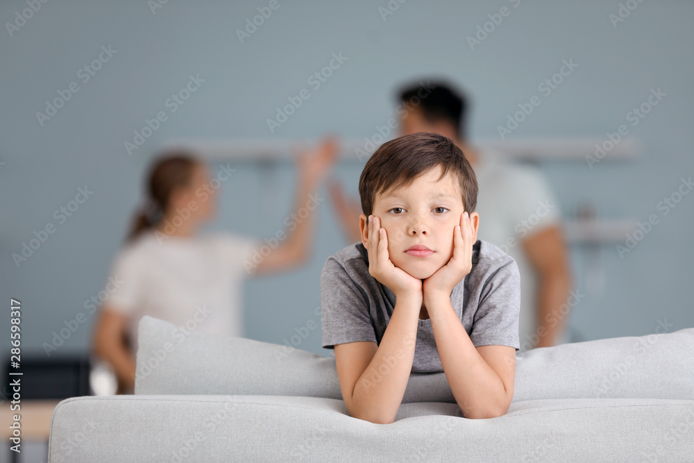 Poster sad little boy and his quarreling parents at home