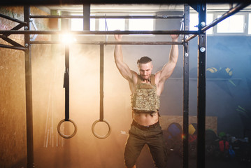 Attractive fitness guy doing pull-ups on the crossbar during training in the modern gym. Close up shot. - Powered by Adobe