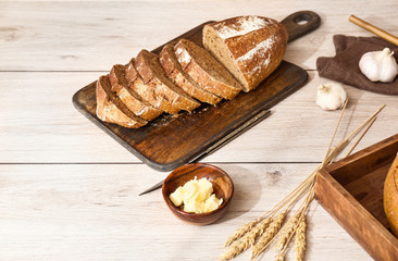Tasty fresh bread with butter on white wooden table