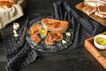 Board with slices of fresh bread, oil and spices on table
