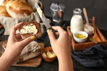 Fototapeta na wymiar Woman spreading butter onto slice of fresh bread, closeup