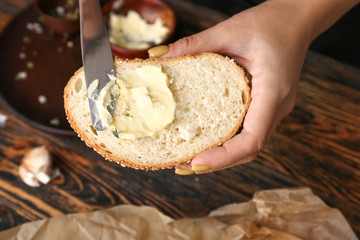 Woman spreading butter onto slice of fresh bread, closeup