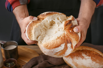 Woman breaking fresh bread, closeup
