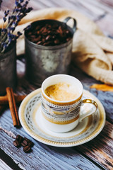 Fototapeta na wymiar Tasse de café en porcelaine ancienne pot en métal cannelle et grains de café sur une table en bois vintage