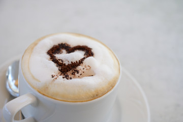 cup of cappuccino with cocoa powder in heart shape on a table in a street cafe, copy space, selected focus, narrow depth of field