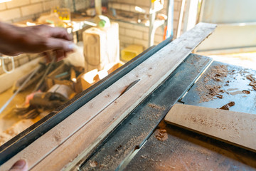 Woodworking machine process a wooden plank. Workers hand hold a wooden plank. Motion blur. Manual wood processing concept.