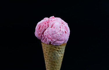 Strawberry ice cream scoop in waffle cone isolated on black background, Closeup Front view Food...