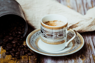 Tasse de café en porcelaine ancienne pot en métal cannelle et grains de café sur une table en bois vintage