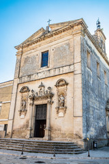 Fototapeta premium The mother church of Cavallino, Lecce, Puglia, Salento, Italy. In baroque style. Wooden portal and niches with statues on the sides, on the facade.