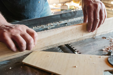 Woodworking machine plane process a wooden plank. Workers hands hold a wooden plank. Motion blur. Manual wood processing concept.