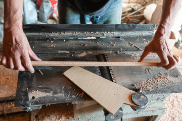 Woodworking machine plane process a wooden plank. Workers hands hold a wooden plank. Manual wood processing concept.