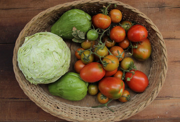 cabbage, chayote, tomato inside wooden basket on wooden background