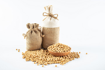 Sacks filled with grain and a bowl of yellow beans on a white background