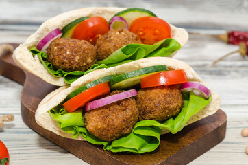 Falafel with vegetables in pita bread on wooden table 