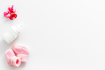 Cute baby clothes for girl, bottle and dummy on white background top view copyspace