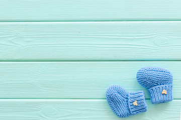 Cute baby booties for boy on mint green wooden background top view copyspace