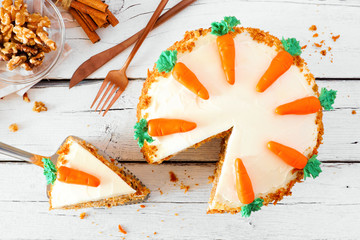 Homemade carrot cake with cream cheese frosting. Above view table scene  with slice being removed....