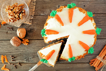 Homemade carrot cake with cream cheese frosting. Top view table scene  with slice being removed....