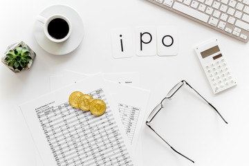 IPO with coins, calculation table, keyboard, coffee on office desk white background top view