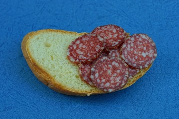 a sandwich of slices of red salami sausage and a long loaf 