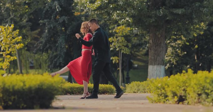 Professional dancers are training tango movements in the park. Dance steps, dancing in the summer street.