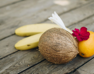 Tropical fruit on the wooden background. Cope space. Fruits background. Coconut, oranges and bananas on a wooden table.