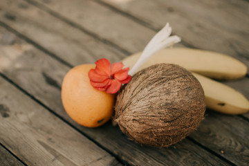 Tropical fruit on the wooden background. Cope space. Fruits background. Coconut, oranges and bananas on a wooden table.