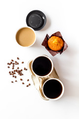 Paper cups with coffee to take away, beans, muffin on white background top view