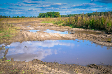 dirty country road among the endless forests and fields after heavy rains somewhere in Eastern Europe.The beginning of autumn 2018