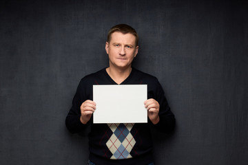 Portrait of thoughtful man holding white blank paper sheet